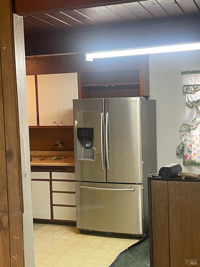 kitchen featuring wooden ceiling, stainless steel fridge, and white cabinets