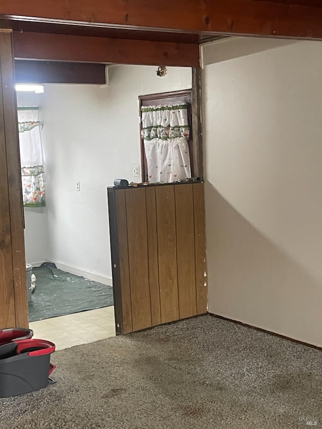 carpeted empty room with beam ceiling