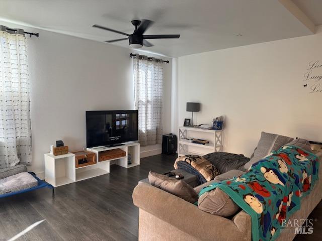 living room featuring dark wood-type flooring and ceiling fan