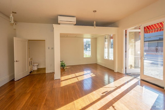 unfurnished dining area with hardwood / wood-style floors and a wall mounted air conditioner