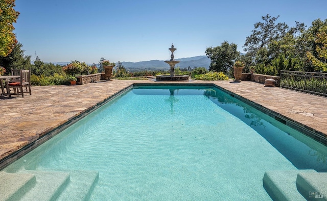 view of swimming pool with a mountain view and a patio area