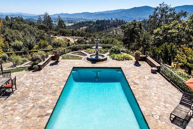 view of swimming pool with a mountain view and a patio