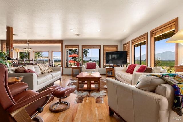 living room with light hardwood / wood-style flooring, a chandelier, and a healthy amount of sunlight