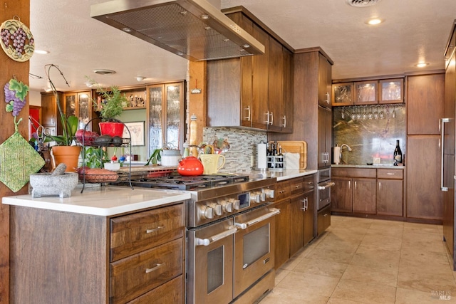 kitchen with light tile patterned flooring, decorative backsplash, range with two ovens, and wall chimney range hood