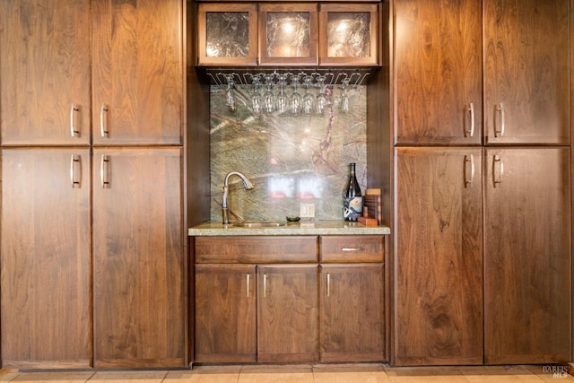 bar featuring sink, light tile patterned floors, and light stone countertops