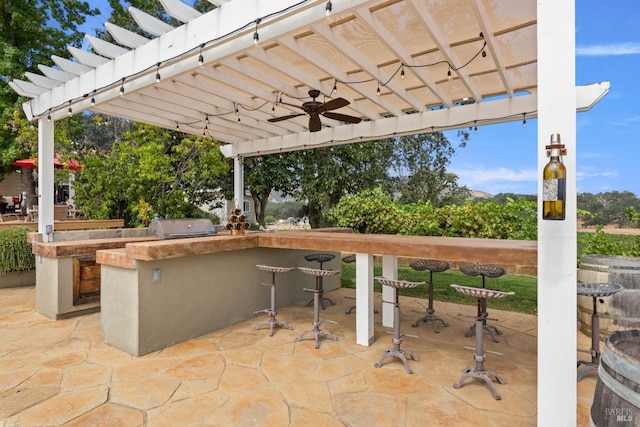 view of patio / terrace with an outdoor bar, ceiling fan, a pergola, a grill, and exterior kitchen