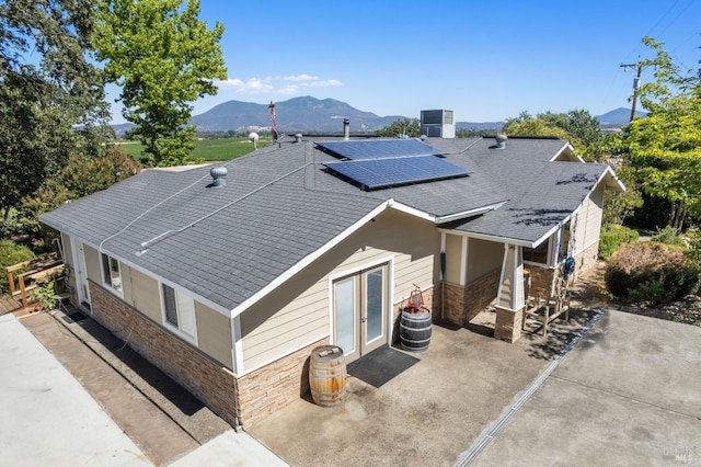 exterior space with cooling unit, a mountain view, and solar panels