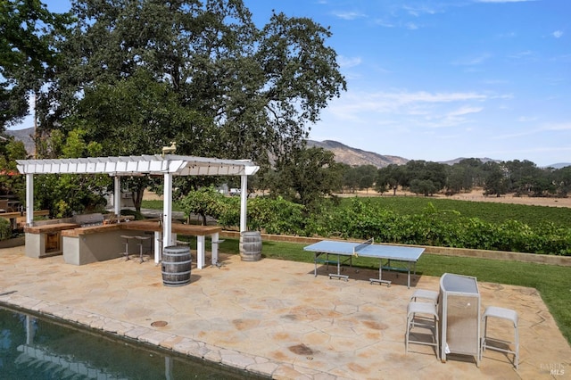 view of patio with a mountain view, a grill, a bar, and a pergola