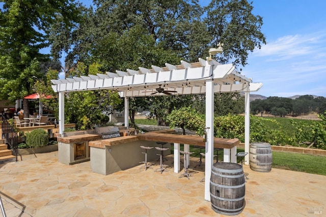 view of patio / terrace with an outdoor kitchen, a grill, a mountain view, and a pergola