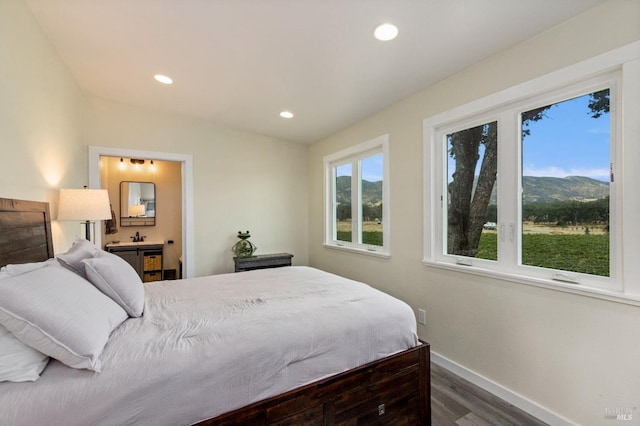 bedroom featuring dark hardwood / wood-style flooring, a mountain view, and ensuite bath