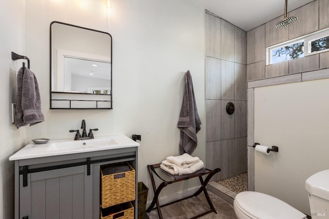 bathroom featuring vanity, toilet, and tiled shower