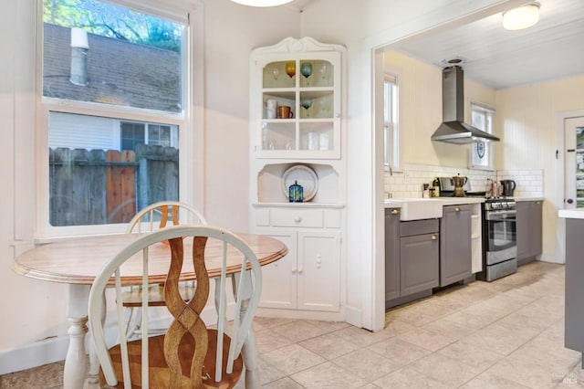 kitchen featuring stainless steel gas stove, backsplash, plenty of natural light, and wall chimney exhaust hood