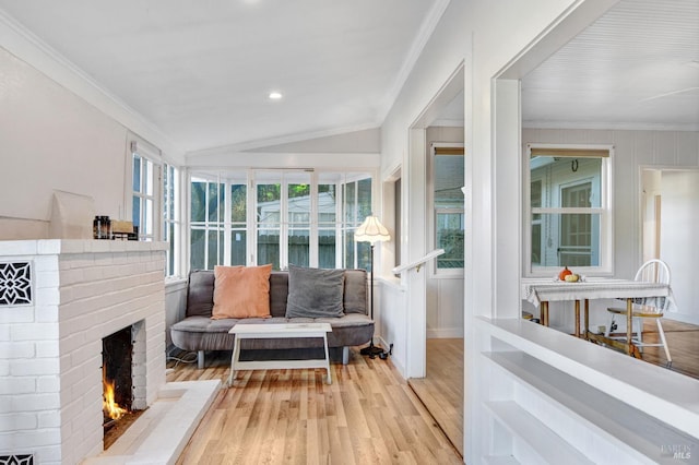 interior space with crown molding, lofted ceiling, light hardwood / wood-style floors, and a brick fireplace