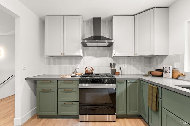 kitchen featuring range with gas cooktop, white cabinetry, backsplash, green cabinetry, and wall chimney exhaust hood