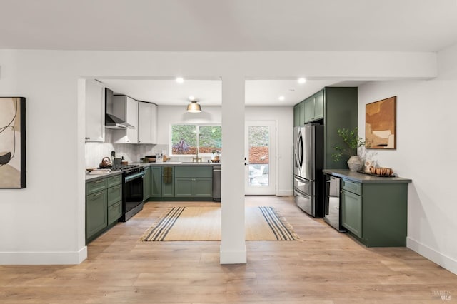 kitchen featuring stainless steel appliances, backsplash, light hardwood / wood-style floors, and green cabinetry