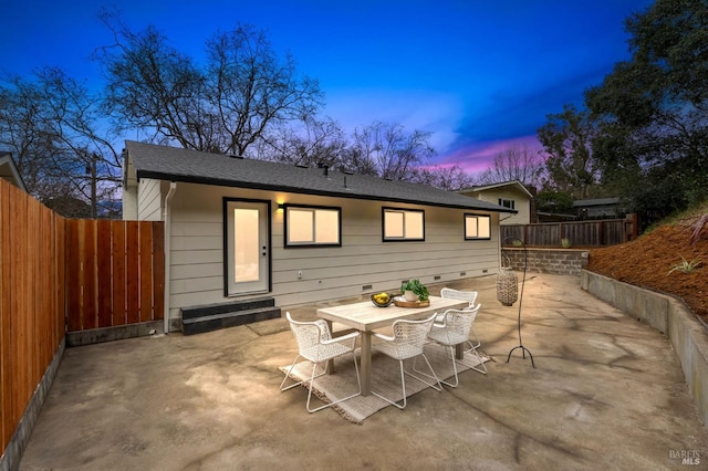 back house at dusk featuring a patio