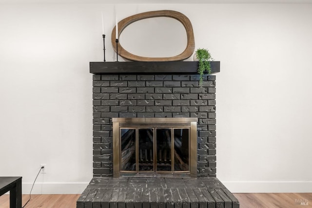 details featuring hardwood / wood-style flooring and a brick fireplace