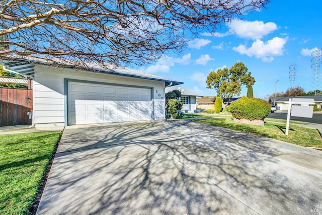 view of front of property with concrete driveway, fence, and a front lawn