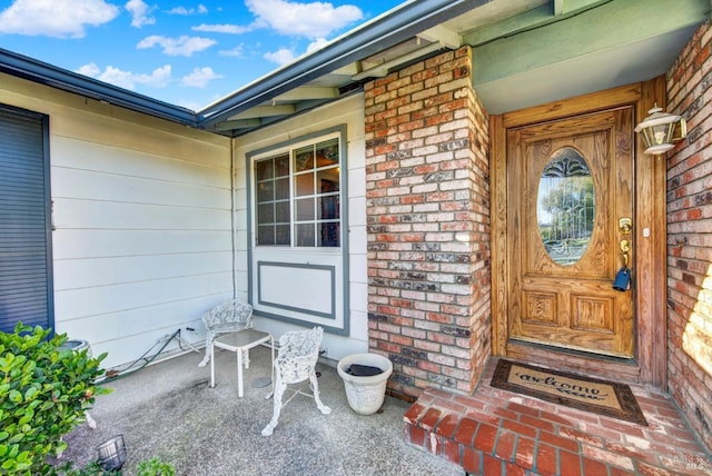 doorway to property featuring brick siding and a porch