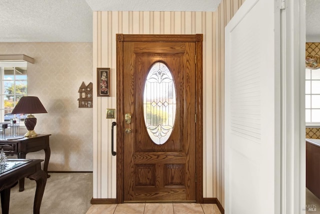 foyer entrance featuring light colored carpet and a textured ceiling