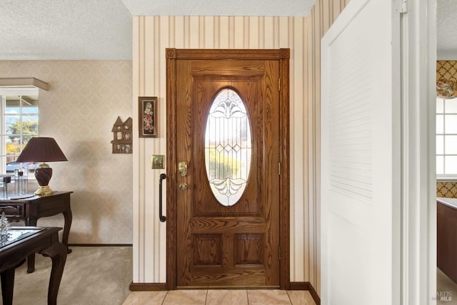 entryway featuring a textured ceiling, wallpapered walls, and baseboards