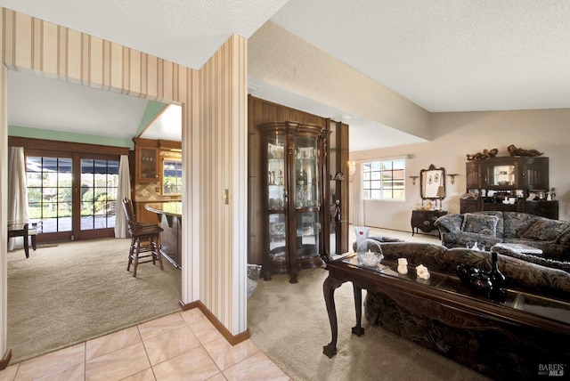 living area with light tile patterned floors, baseboards, light carpet, and a textured ceiling