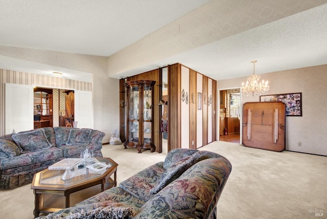 living area featuring a textured ceiling, wallpapered walls, carpet flooring, and an inviting chandelier