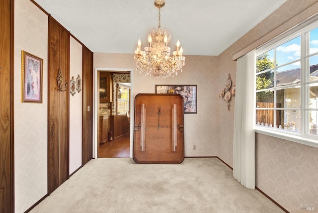 interior space with plenty of natural light, light carpet, and a chandelier