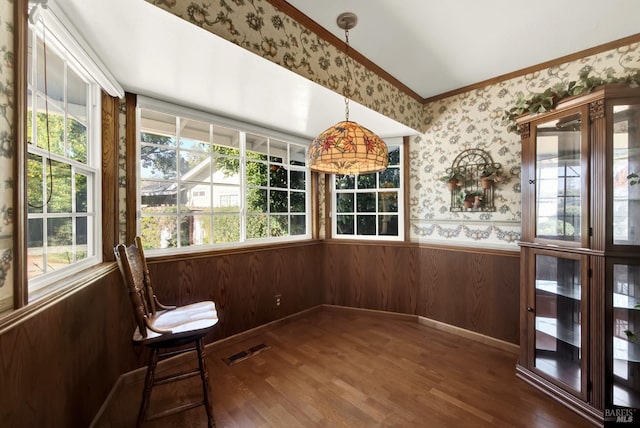 unfurnished sunroom featuring wallpapered walls, ornamental molding, visible vents, wainscoting, and wood finished floors