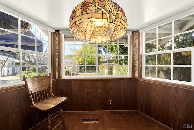 unfurnished sunroom with wooden walls, visible vents, and wood finished floors