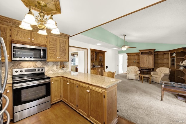 kitchen with tasteful backsplash, stainless steel appliances, a peninsula, ceiling fan with notable chandelier, and lofted ceiling