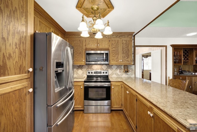 kitchen with light hardwood / wood-style flooring, hanging light fixtures, appliances with stainless steel finishes, a notable chandelier, and backsplash