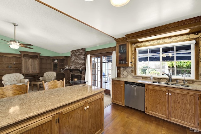 kitchen with a ceiling fan, vaulted ceiling, wood finished floors, dishwasher, and a sink