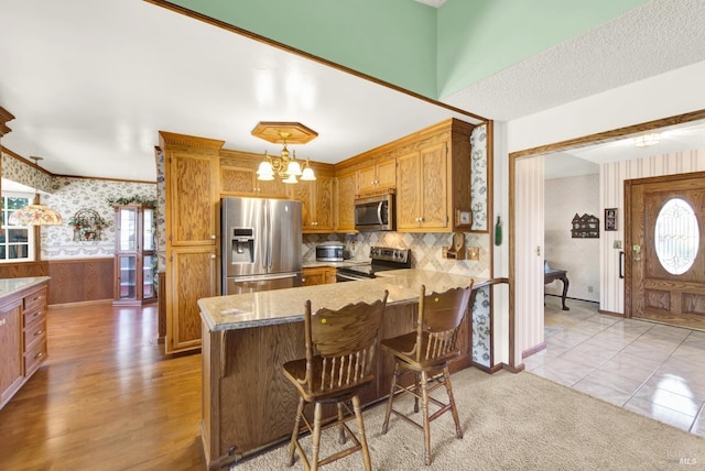 kitchen featuring a chandelier, hanging light fixtures, a kitchen breakfast bar, kitchen peninsula, and stainless steel appliances