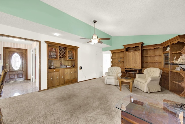 sitting room with baseboards, ceiling fan, a textured ceiling, light colored carpet, and lofted ceiling