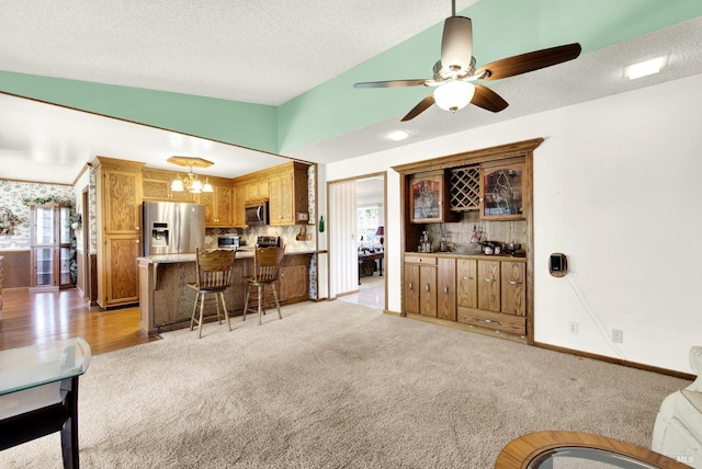 living room featuring light carpet, a healthy amount of sunlight, ceiling fan with notable chandelier, and a textured ceiling