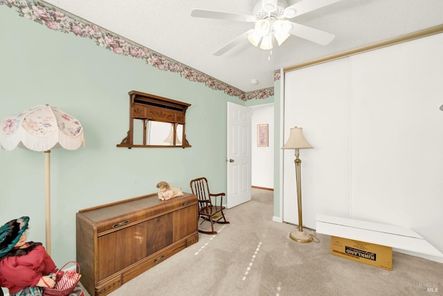 interior space featuring ceiling fan, light carpet, and a textured ceiling