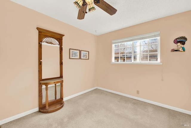 carpeted empty room with ceiling fan and baseboards