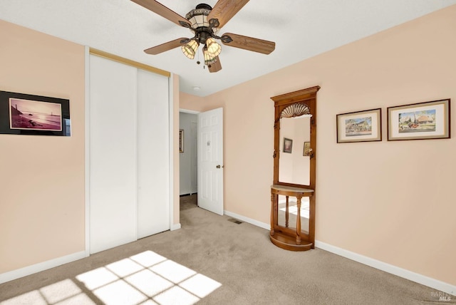 unfurnished bedroom with a closet, a ceiling fan, visible vents, light carpet, and baseboards