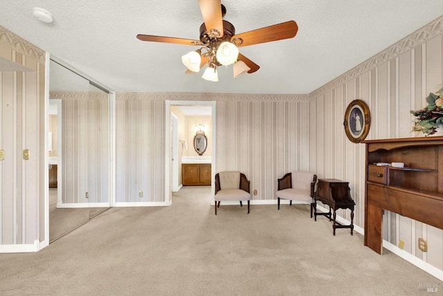 living area featuring light carpet, ceiling fan, and a textured ceiling