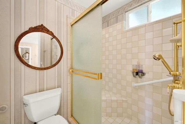 bathroom with a decorative wall, toilet, and a shower stall