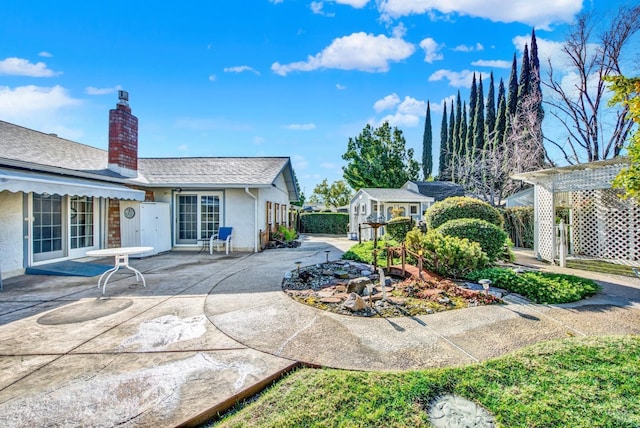 back of property featuring stucco siding, an outdoor structure, a patio, fence, and a chimney