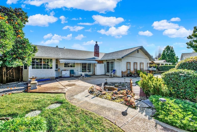 back of property with a shingled roof, a chimney, fence, a patio, and stucco siding