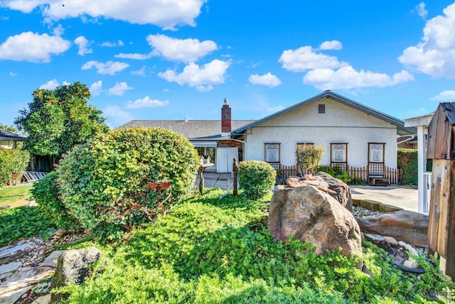 single story home with stucco siding and a chimney