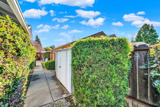 view of side of property with a storage shed, a patio area, fence, and an outdoor structure