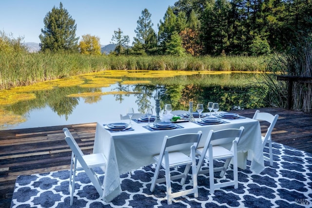 view of dock featuring outdoor dining area and a water view