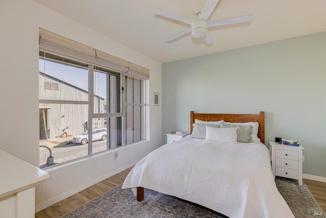 bedroom with dark wood-style floors, a ceiling fan, and baseboards