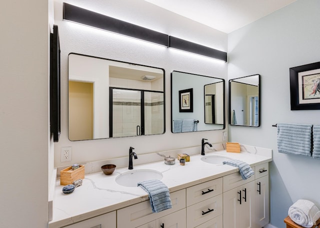 full bathroom featuring double vanity, a sink, and a shower stall