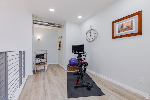 workout area featuring recessed lighting, baseboards, and light wood finished floors