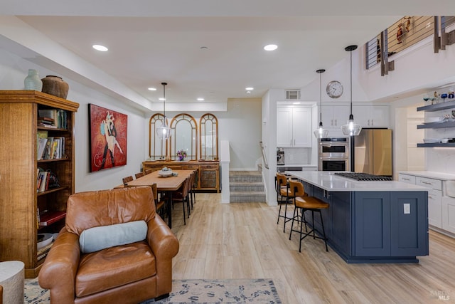 kitchen with light countertops, hanging light fixtures, freestanding refrigerator, white cabinetry, and a kitchen island